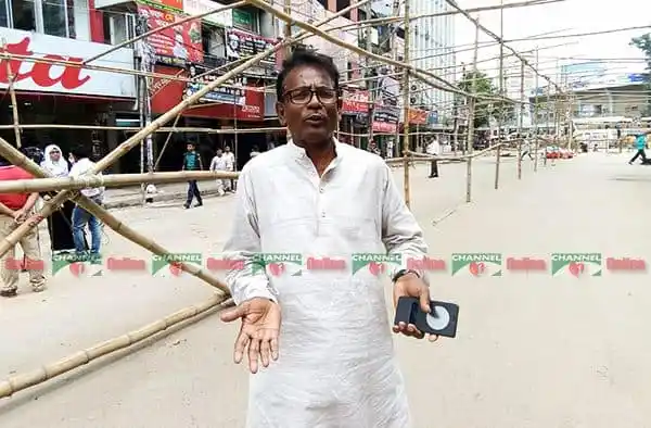 বাংলাদেশের একজন ব্যক্তি রাস্তার পাশে দাঁড়িয়ে কথা বলছেন. Channel i News - চ্যানেল আই নিউজ