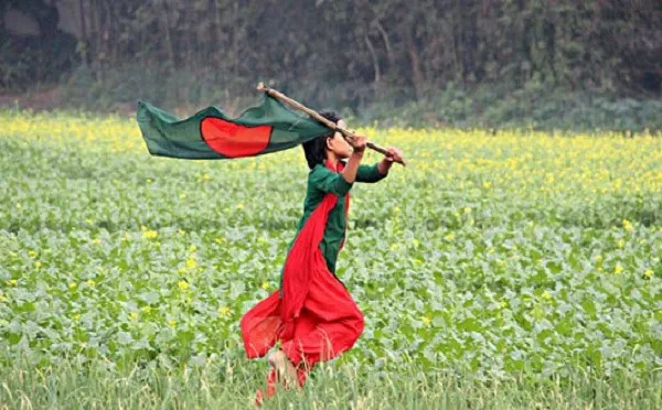 একজন নারী পতাকা হাতে বাংলাদেশের পতাকা বহন করছেন. Channel i News - চ্যানেল আই নিউজ