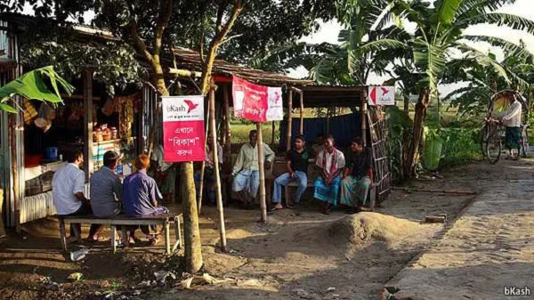 বাংলাদেশের গ্রামীণ বাজারে মানুষজন বসে আলোচনা করছে।. Channel i News - চ্যানেল আই নিউজ