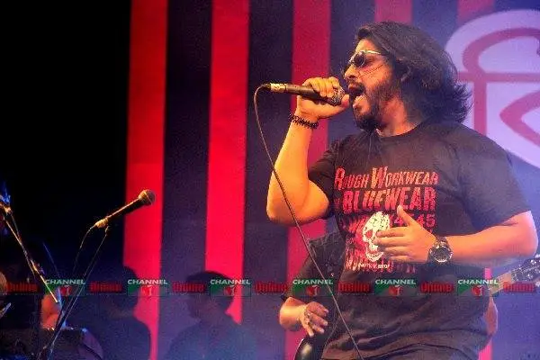 ব্যান্ডের গায়ক স্টেজে গান গাইছেন, কালো টি-শার্ট পরা. Channel i News - চ্যানেল আই নিউজ