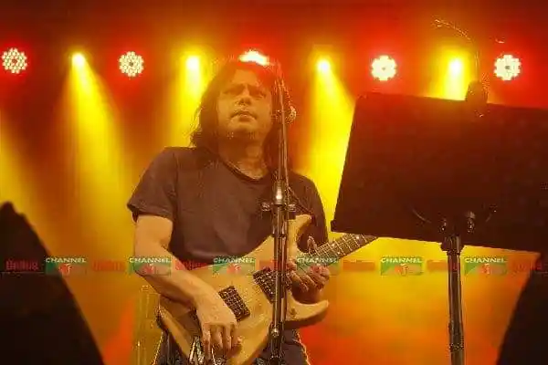 প্রসিদ্ধ গায়ক স্টেজে গিটার বাজাচ্ছেন, আলো ঝলমলে পরিবেশ. Channel i News - চ্যানেল আই নিউজ