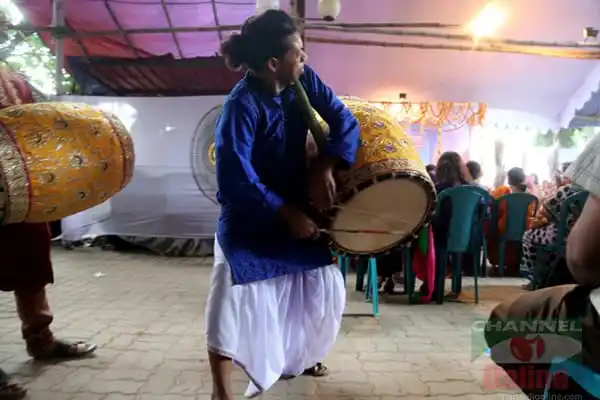 শিল্পী দোলনায় বাজাচ্ছেন ঢোল, উৎসবের পরিবেশে লোকজন উপস্থিত. Channel i News - চ্যানেল আই নিউজ