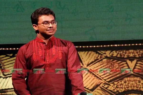 Young man in traditional red attire on stage at Channel i Online event. Channel i News - চ্যানেল আই নিউজ