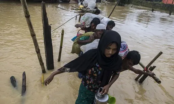 Flood-affected people crossing water with makeshift boats and bamboo poles. Channel i News - চ্যানেল আই নিউজ