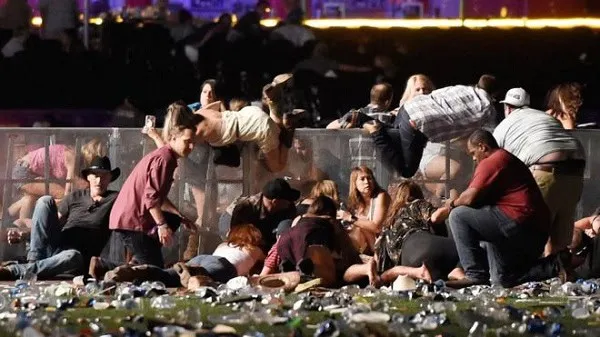 Las Vegas shooting aftermath with people gathering and debris on the ground. Channel i News - চ্যানেল আই নিউজ