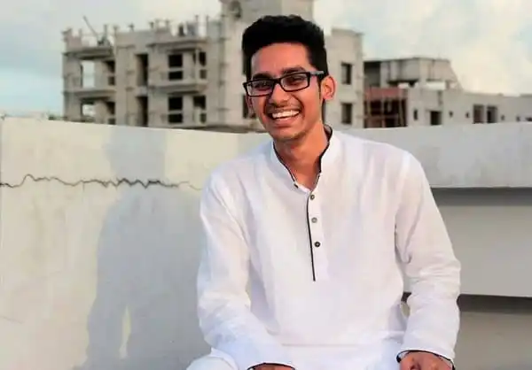 খুশি যুবক ছেলেটি ছাদে বসে হাসছে, পটভূমিতে শহরের ভবন।. Channel i News - চ্যানেল আই নিউজ