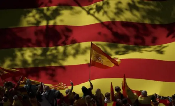 Spanish flag at a rally with people holding flags and banners. Channel i News - চ্যানেল আই নিউজ