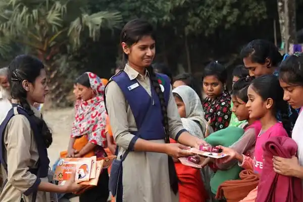 শিক্ষার্থীদের হাতে বই বিতরণ করছে এক শিক্ষিকা. Channel i News - চ্যানেল আই নিউজ