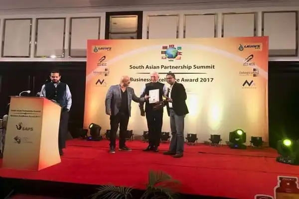 অভিনন্দন প্রদান অনুষ্ঠানে তিন ব্যক্তি হাতে পুরস্কার গ্রহণ করছেন. Channel i News - চ্যানেল আই নিউজ