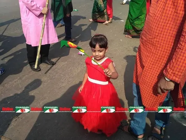 ছোট শিশু লাল পোশাক পরে পতাকা হাতে নিয়ে উৎসব করছে. Channel i News - চ্যানেল আই নিউজ