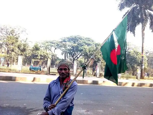বাংলাদেশি কৃষক ফুল মিয়া জাতীয় পতাকা হাতে নিয়ে দাঁড়িয়ে. Channel i News - চ্যানেল আই নিউজ