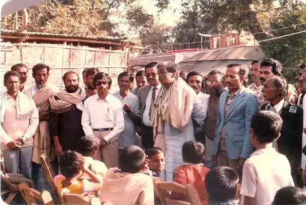 জনপ্রিয় রাজনৈতিক নেতা জনসম্মুখে বক্তৃতা দিচ্ছেন, আশেপাশে উপস্থিত দর্শকরা শুনছেন. Channel i News - চ্যানেল আই নিউজ
