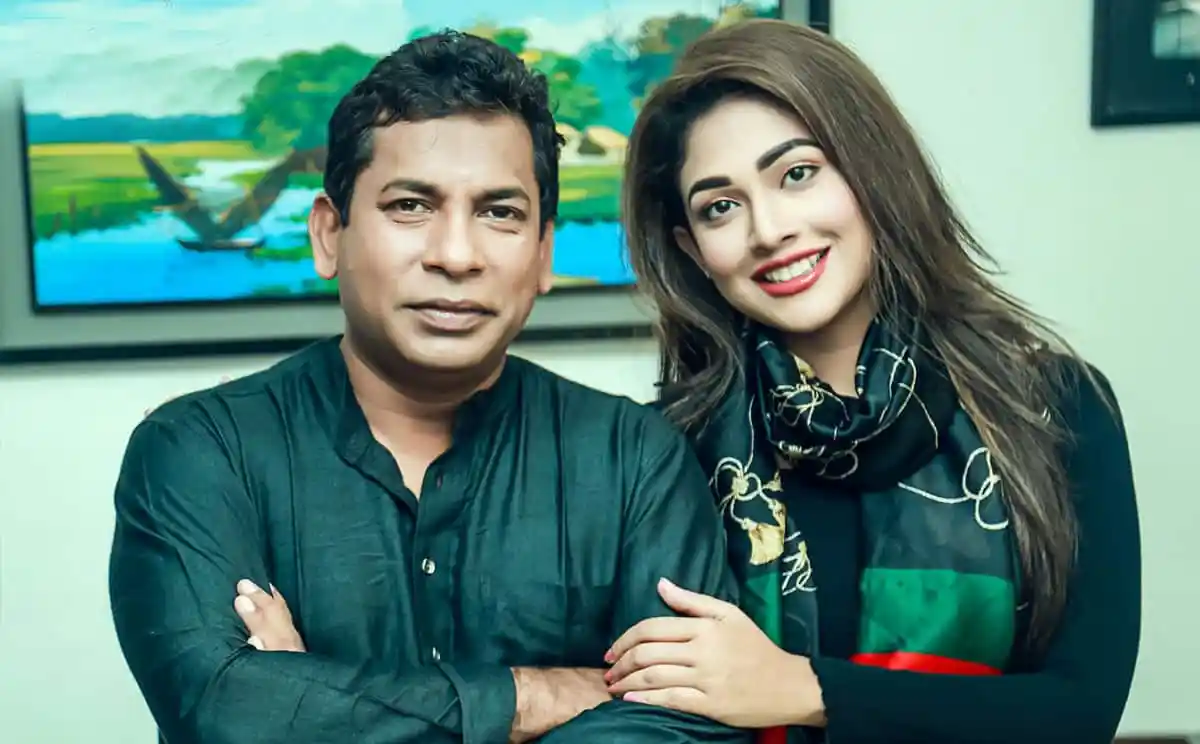 দুজন ব্যক্তি হাসিমুখে দাঁড়িয়ে, পেছনে বিমানবন্দর দৃশ্যের ছবি. Channel i News - চ্যানেল আই নিউজ