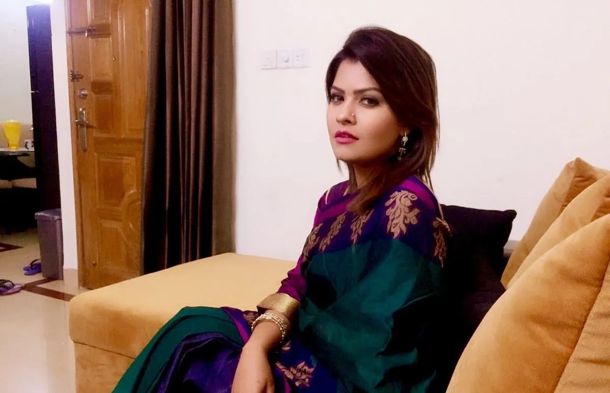 তাসনুভা এলভিন বসে আছেন একটি সোফায়, পেছনে দরজা ও জানালা দেখা যাচ্ছে. Channel i News - চ্যানেল আই নিউজ