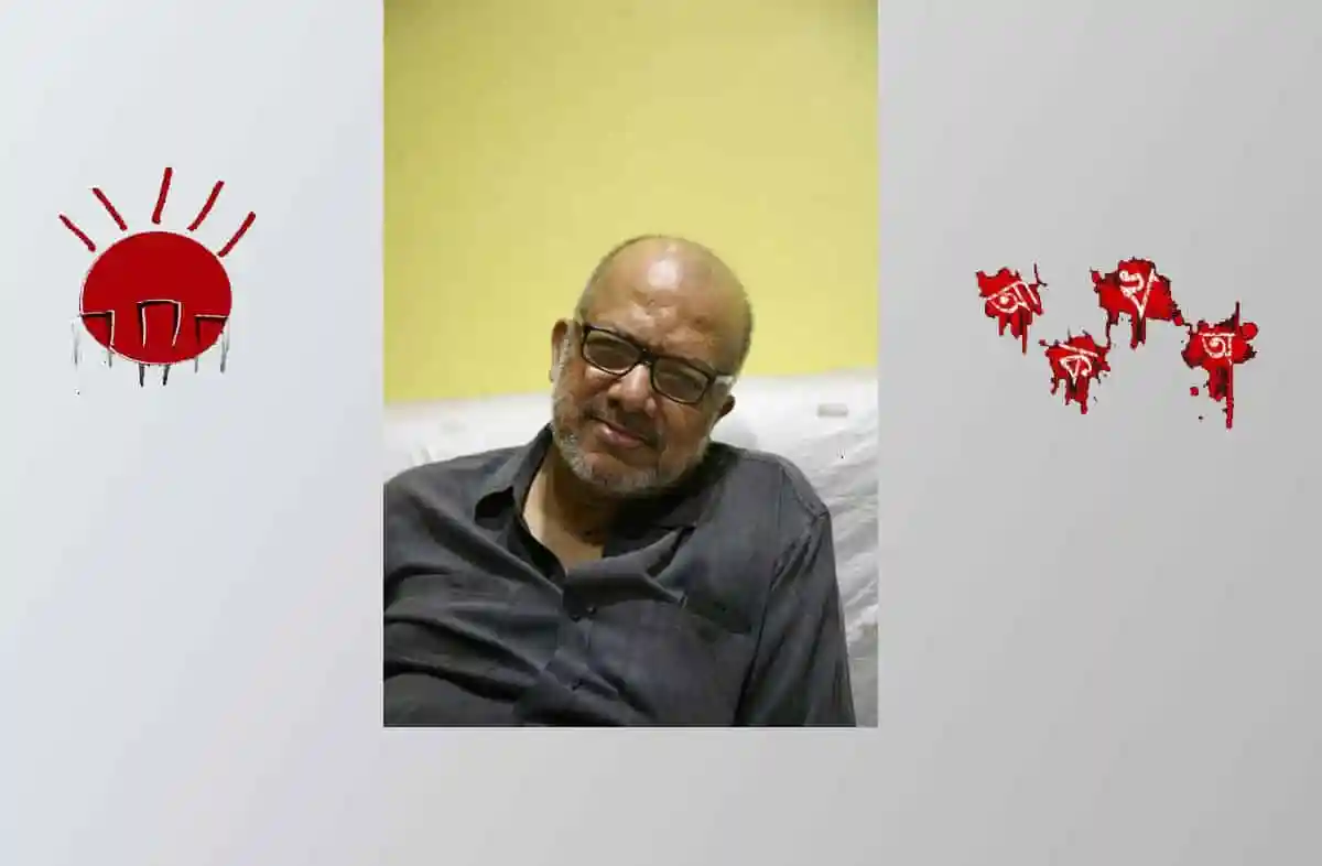 বয়স্ক ব্যক্তি চেয়ারে বসে হাসছেন, কালো পোশাক পরা. Channel i News - চ্যানেল আই নিউজ