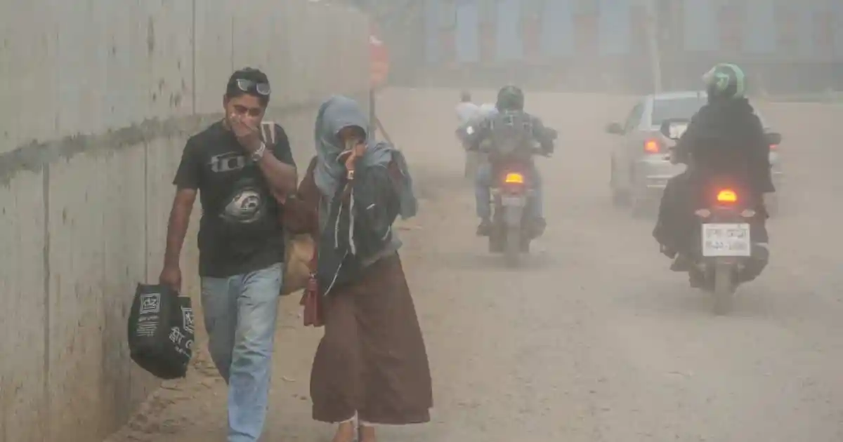 ধুলাবালির কারণে মানুষজন রাস্তার পাশে হাঁটছে, বাইক ও গাড়ি চলাচল করছে. Channel i News - চ্যানেল আই নিউজ