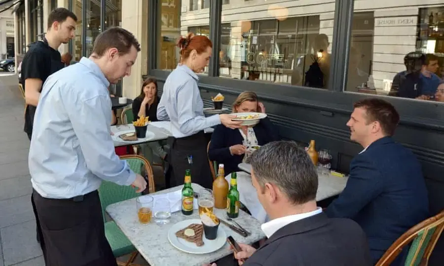International restaurant scene with waiters serving customers in a modern setting. Channel i News - চ্যানেল আই নিউজ