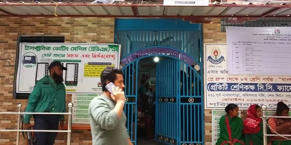 একজন নারী মোবাইল ফোনে কথা বলছেন, অন্যরা অপেক্ষা করছে. Channel i News - চ্যানেল আই নিউজ