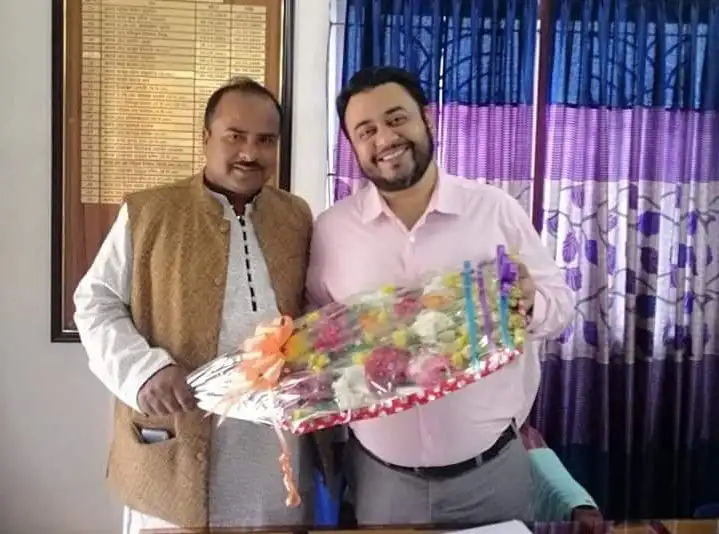 দুই খাদ্য কর্মকর্তা বদলি নিয়ে আলোচনা করছেন, ফুলের তোড়া হাতে. Channel i News - চ্যানেল আই নিউজ