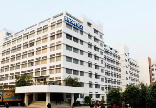 SNOWTEX কারখানা ভবন, ঢাকার আশেপাশে গাছপালা ও মানুষ দেখা যাচ্ছে. Channel i News - চ্যানেল আই নিউজ