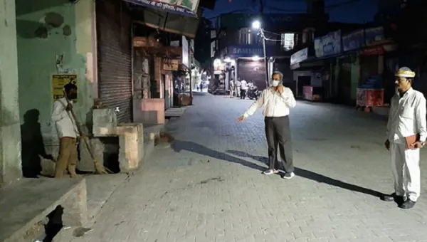 Empty street in Bangladesh at night with three men wearing masks and social distancing. Channel i News - চ্যানেল আই নিউজ
