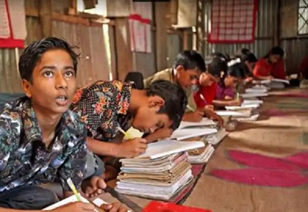 প্রাথমিক শিক্ষার্থীরা ক্লাসে বই পড়ছে ও লেখার অনুশীলন করছে. Channel i News - চ্যানেল আই নিউজ