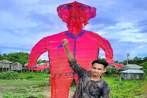 একজন যুবক বড় আকারের ঘুড়ির সামনে দাঁড়িয়ে হাসছে. Channel i News - চ্যানেল আই নিউজ
