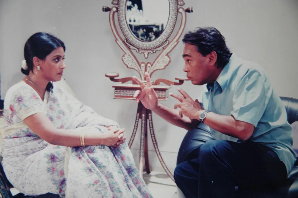 Two people engaged in a serious conversation in a room. Channel i News - চ্যানেল আই নিউজ