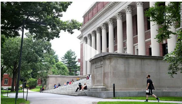 Students sitting on steps outside a historic building with columns in a university campus. Channel i News - চ্যানেল আই নিউজ