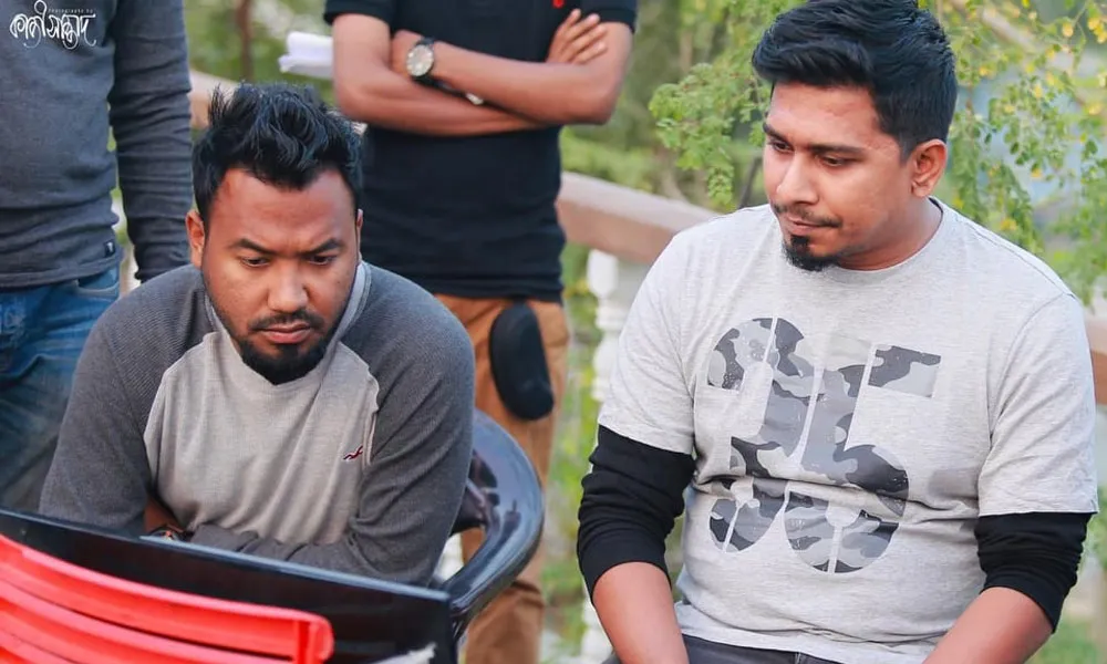 দুটি পুরুষ একটি ক্যামেরার স্ক্রিন দেখছেন, অন্যরা পেছনে দাঁড়িয়ে. Channel i News - চ্যানেল আই নিউজ