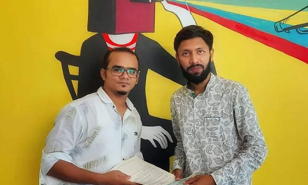 তবীবের প্রথম গান প্রকাশের সময়ের ছবি, দুই ব্যক্তি হাতে কাগজ নিয়ে দাঁড়িয়ে. Channel i News - চ্যানেল আই নিউজ
