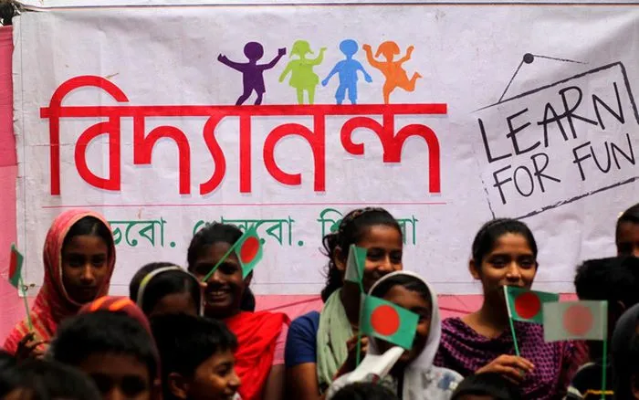 Children holding Bangladeshi flags at a school event in Bangladesh. Channel i News - চ্যানেল আই নিউজ
