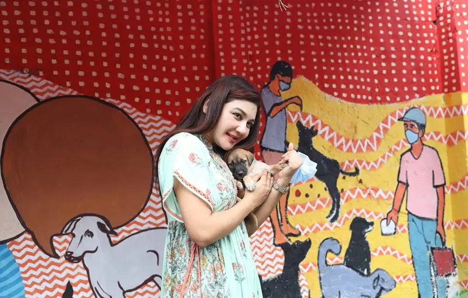 মহিলা কুকুরের সাথে খেলা করছেন, পটভূমিতে রঙিন চিত্রাঙ্কন।. Channel i News - চ্যানেল আই নিউজ