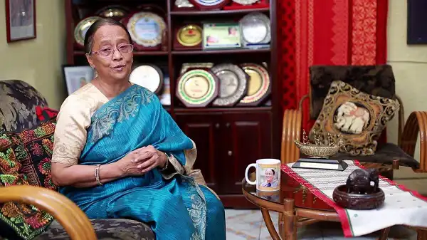 সেলিনা হোসেন বসে আছেন ঘরে, পটভূমিতে আসবাবপত্র ও সাজসজ্জা. Channel i News - চ্যানেল আই নিউজ