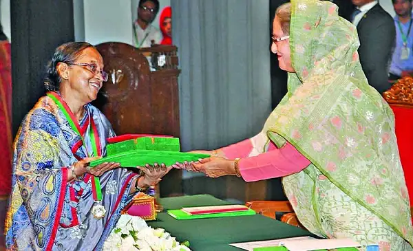 সেলিনা হোসেনের হাতে পুরস্কার গ্রহণ করছেন একজন নারী. Channel i News - চ্যানেল আই নিউজ
