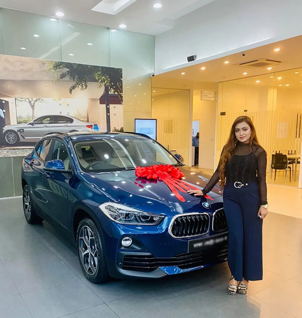নারী বিক্রেতা বিএমডব্লিউ গাড়ির পাশে দাঁড়িয়ে. Channel i News - চ্যানেল আই নিউজ