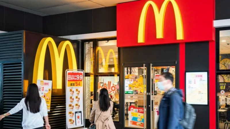 McDonald's restaurant entrance with golden arches and promotional signs in Bengali. Channel i News - চ্যানেল আই নিউজ