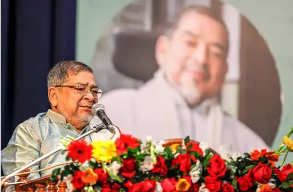 কাজী শাহেদ আহমেদ বক্তৃতা দিচ্ছেন, পেছনে বড় ছবি. Channel i News - চ্যানেল আই নিউজ