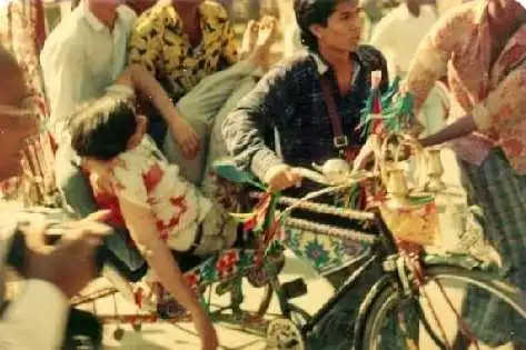 বাইক চালাচ্ছেন এক যুবক, পাশে শিশু ও অন্যান্য মানুষজন উপস্থিত. Channel i News - চ্যানেল আই নিউজ
