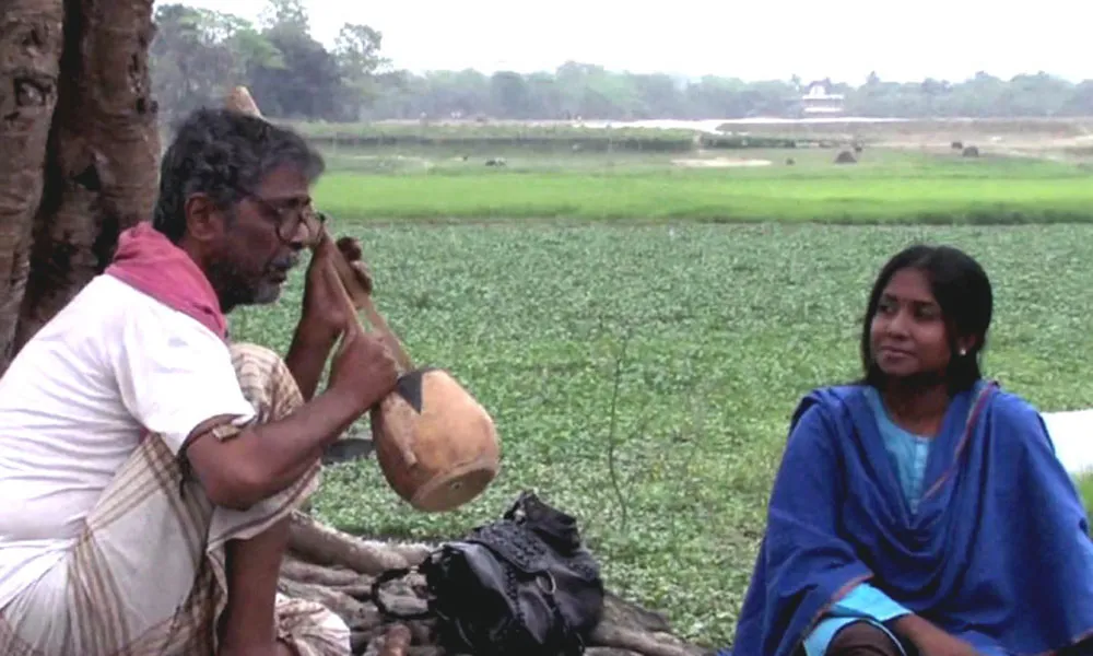 Bengali fisherman smoking water pipe near a riverbank. Channel i News - চ্যানেল আই নিউজ