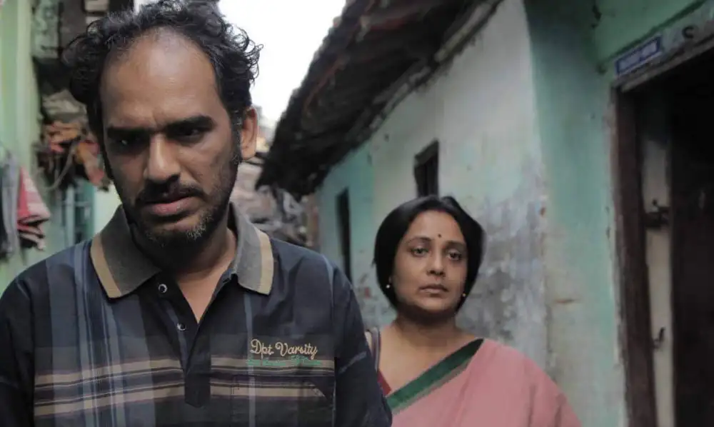 দুজন ব্যক্তি একটি পুরনো এলাকায় হাঁটছেন, একজনের মুখের অভিব্যক্তি গম্ভীর।. Channel i News - চ্যানেল আই নিউজ