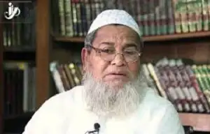 বয়স্ক মুসলিম ধর্মীয় নেতা বইয়ের সামনে বসে আলোচনা করছেন. Channel i News - চ্যানেল আই নিউজ