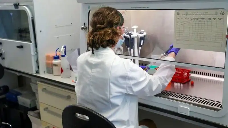 Scientist working in a lab with protective gear and lab equipment. Channel i News - চ্যানেল আই নিউজ