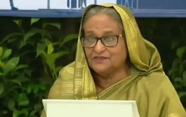 প্রধানমন্ত্রী ভাষণ দিচ্ছেন, পেছনে সবুজ গাছের পাতা. Channel i News - চ্যানেল আই নিউজ
