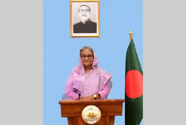প্রধানমন্ত্রী জাতীয় সংসদে ভাষণ দিচ্ছেন, পেছনে বাংলাদেশের পতাকা ও ছবি।. Channel i News - চ্যানেল আই নিউজ
