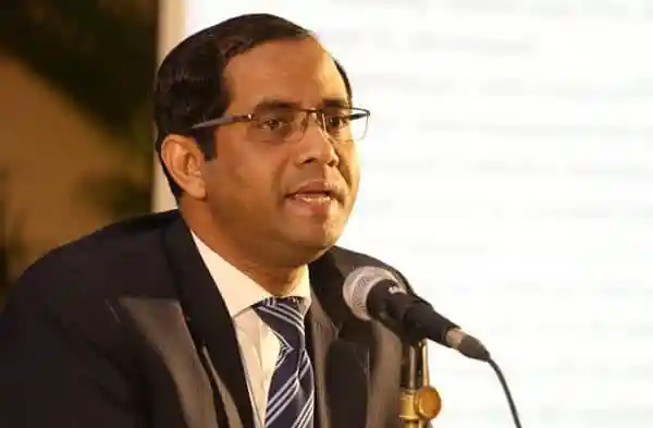 বাংলাদেশের একজন সরকারি কর্মকর্তা বক্তৃতা দিচ্ছেন, পেছনে স্ক্রিনে তথ্য দেখানো হচ্ছে. Channel i News - চ্যানেল আই নিউজ