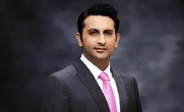Professional portrait of a man in a suit with a pink tie against a dark background. Channel i News - চ্যানেল আই নিউজ