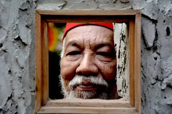 বৃদ্ধ শিল্পীর মুখ ছোট জানালার মধ্যে দেখা যাচ্ছে. Channel i News - চ্যানেল আই নিউজ