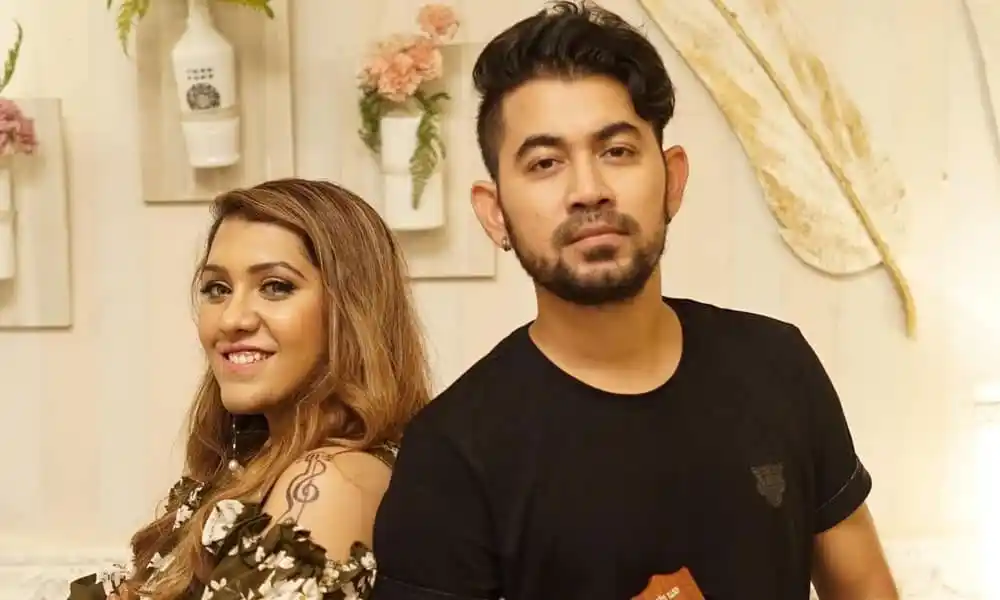 দুটি মানুষ হাসিমুখে দাঁড়িয়ে, পেছনে ফুলের সাজসজ্জা. Channel i News - চ্যানেল আই নিউজ