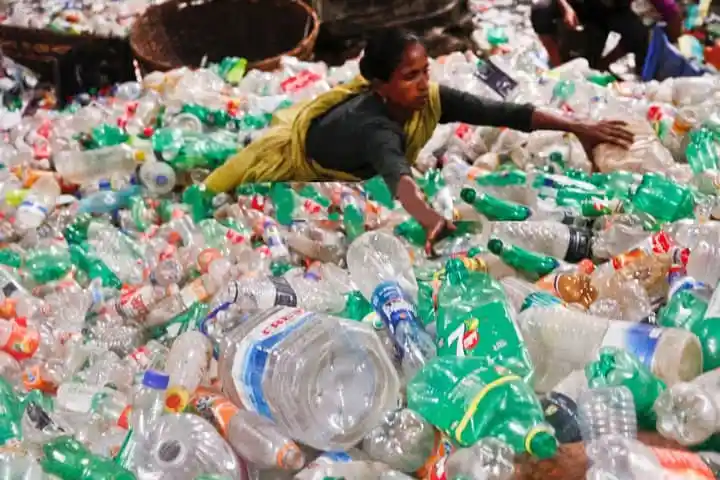 Woman amidst large pile of plastic bottles and waste in Bangladesh. Channel i News - চ্যানেল আই নিউজ
